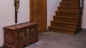 A staircase with wooden steps and a black handrail, a wooden door, and a wooden cabinet with decorative carvings.