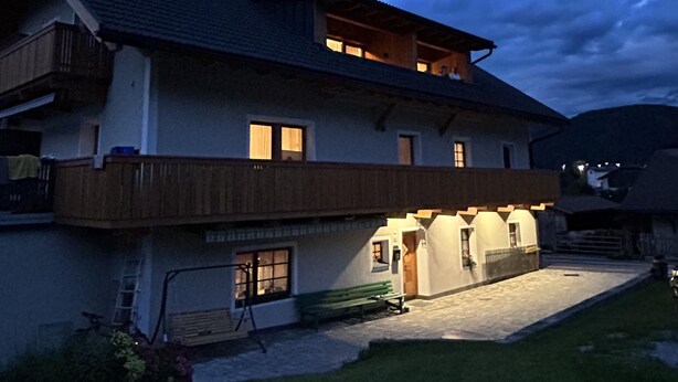 A two-story house with a balcony, a front porch, and a small garden area.