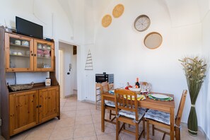 A dining area with a wooden table, chairs, a buffet cabinet, a television, and wall decorations.