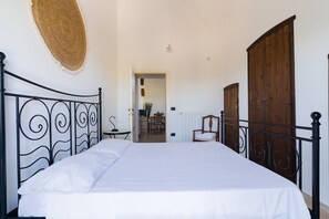 A bedroom with a bed, a wooden wardrobe, a door, and a woven wall hanging.