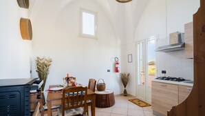 Una cocina con zona de comedor, una ventana, un extintor y una puerta que da a un balcón.