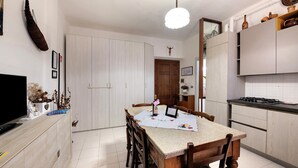 A modern kitchen with a dining table, chairs, a TV, and cabinets. - Casa Vacanze Da Rosa Apartment – Step-Free Access, Family-Friendly, Central Iseo (Iseo)