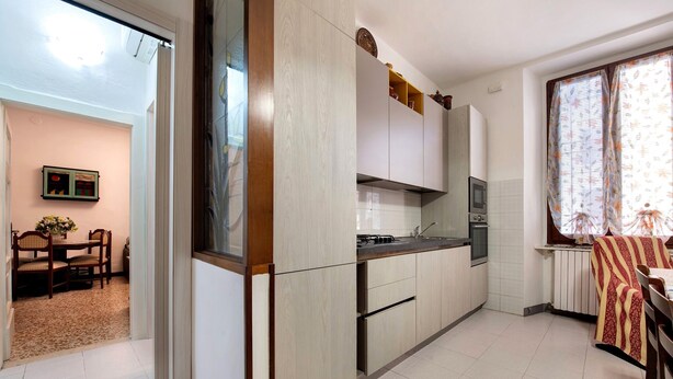 A modern kitchen with white cabinets, a built-in oven, and a dining area with a table and chairs. - Casa Vacanze Da Rosa Apartment – Step-Free Access, Family-Friendly, Central Iseo (Iseo)