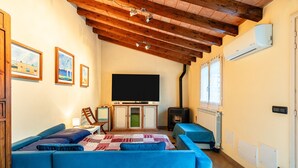 A cozy living room with a sofa, a TV, a cabinet, and a wood-burning stove. - Dependance 'Residence Al Pozzo' with Wi-Fi and Air Conditioning (Capannori)