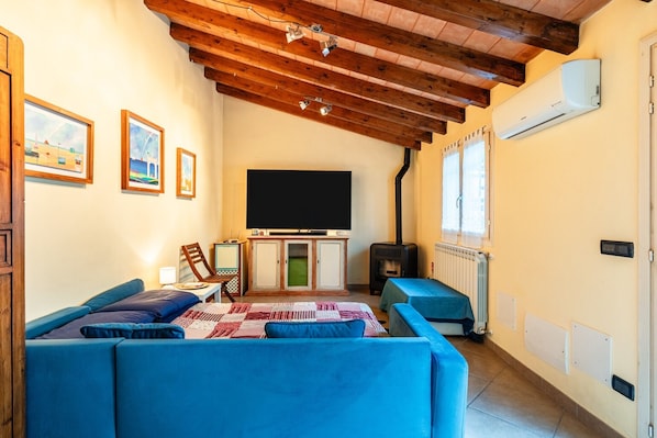 A cozy living room with a sofa, a TV, a cabinet, and a wood-burning stove.