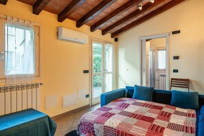 A room with a bed, a table, a chair, a radiator, and a window.