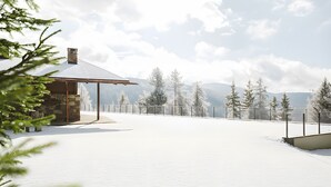 A snow-covered landscape with a stone building and a metal fence.