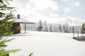 Ett snötäckt landskap med en byggnad av sten och ett staket av metall.