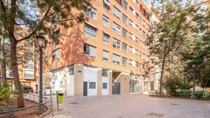 Un edificio de varios pisos con fachada de ladrillo, ventanas grandes y un patio empedrado.
