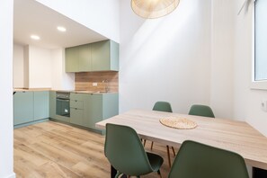 Eine moderne Küche mit grünen Schränken, einem Holztisch und grünen Stühlen.
