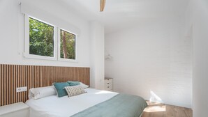 Un dormitorio con cama, mesitas de noche, ventana y cabecera de madera.