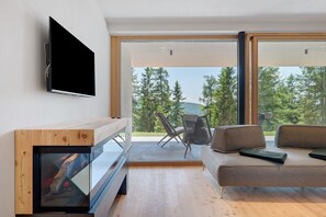 En moderne stue med et fladskærms-tv, en sofa og et spiseområde med stole.