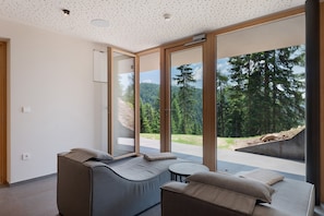 Une pièce moderne dotée d’une grande porte-fenêtre coulissante, d’un canapé et d’une petite table.