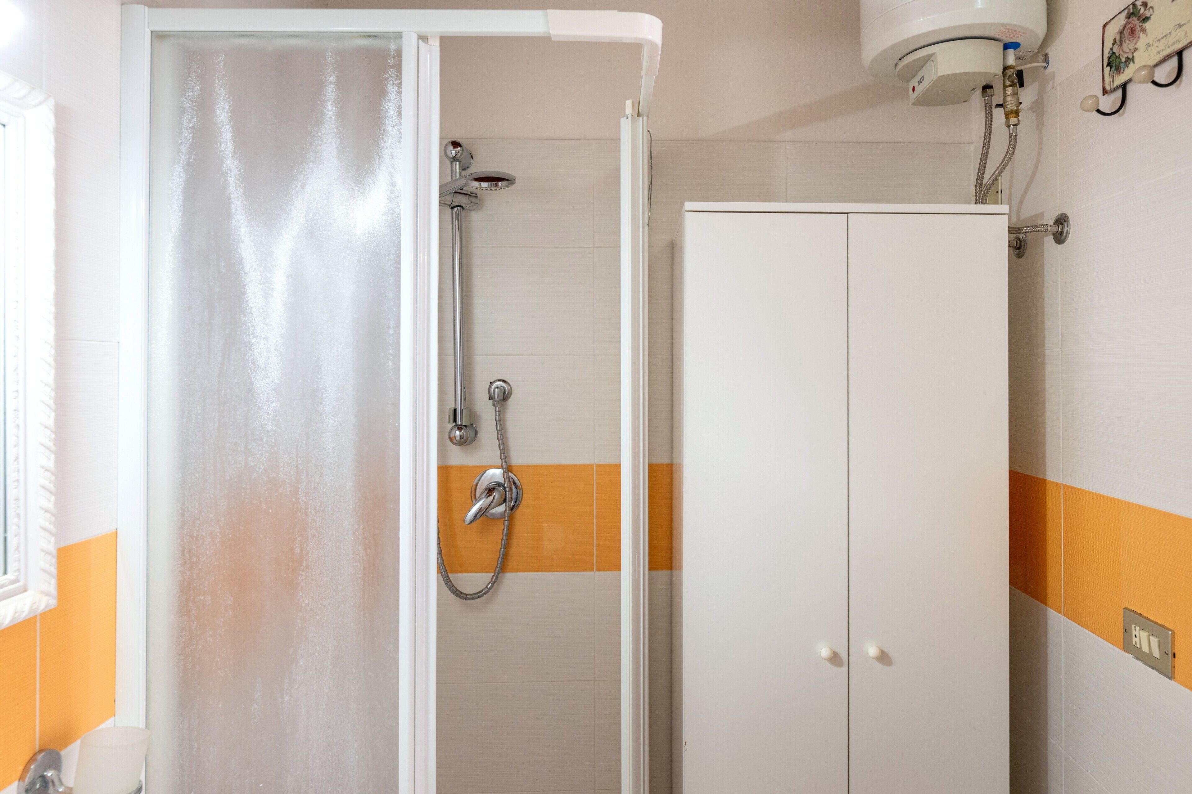 A bathroom with a shower, a toilet, and a cabinet.