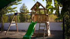 Un'area giochi con uno scivolo di legno, una struttura per arrampicata e un’altalena.