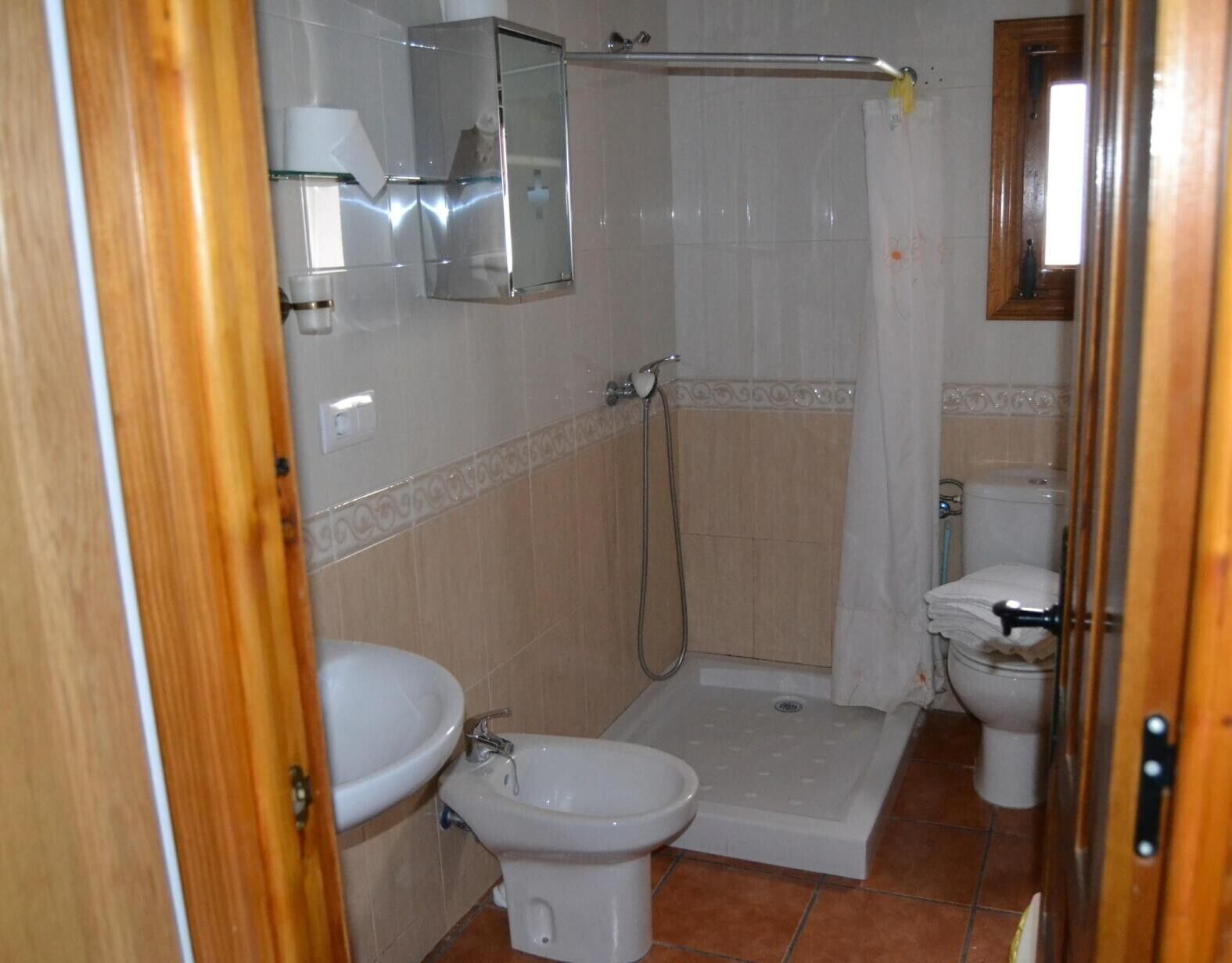 A bathroom with a bidet, toilet, and a shower area.