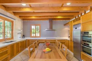 Una cocina moderna con armarios de madera, un refrigerador de acero inoxidable y una mesa de comedor con sillas.