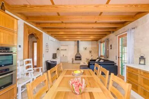 Un comedor con mesa de madera, sillas y un frutero.