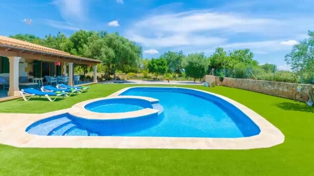 A swimming pool with a circular design, surrounded by green lawn and lounge chairs. - Villa 'Sa Sargantana' with Private Pool, Private Terrace and Wi-Fi (Illes Balears)