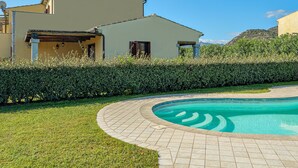 Una casa con piscina, jardín y cielo azul despejado.