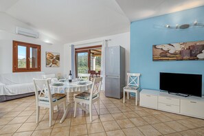 Un coin repas avec une table dressée pour deux personnes, un téléviseur et un réfrigérateur.