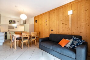 Una sala de estar con un sofá gris, una mesa de comedor de madera y sillas.