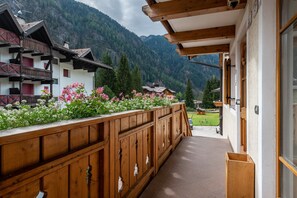 Un balcón de madera con vistas a un paisaje montañoso, una valla de madera y un edificio con techo inclinado.