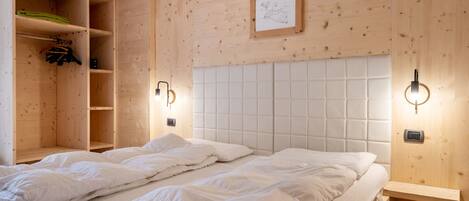 Une chambre avec un lit, une armoire en bois et des lampes fixées au mur.