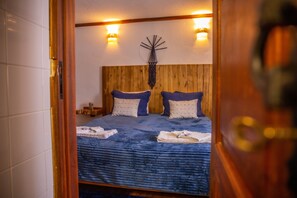 A bedroom with a wooden headboard, two bedside tables, and a wall-mounted clock.