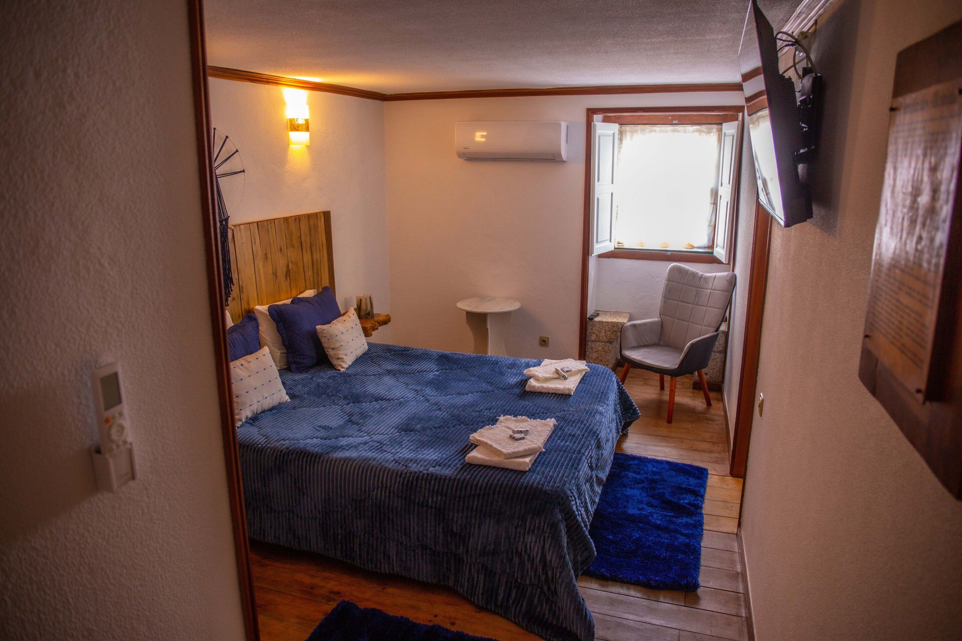 Ein Schlafzimmer mit Bett, Nachttisch, Stuhl und einem kleinen Tisch mit Sitzgelegenheit.