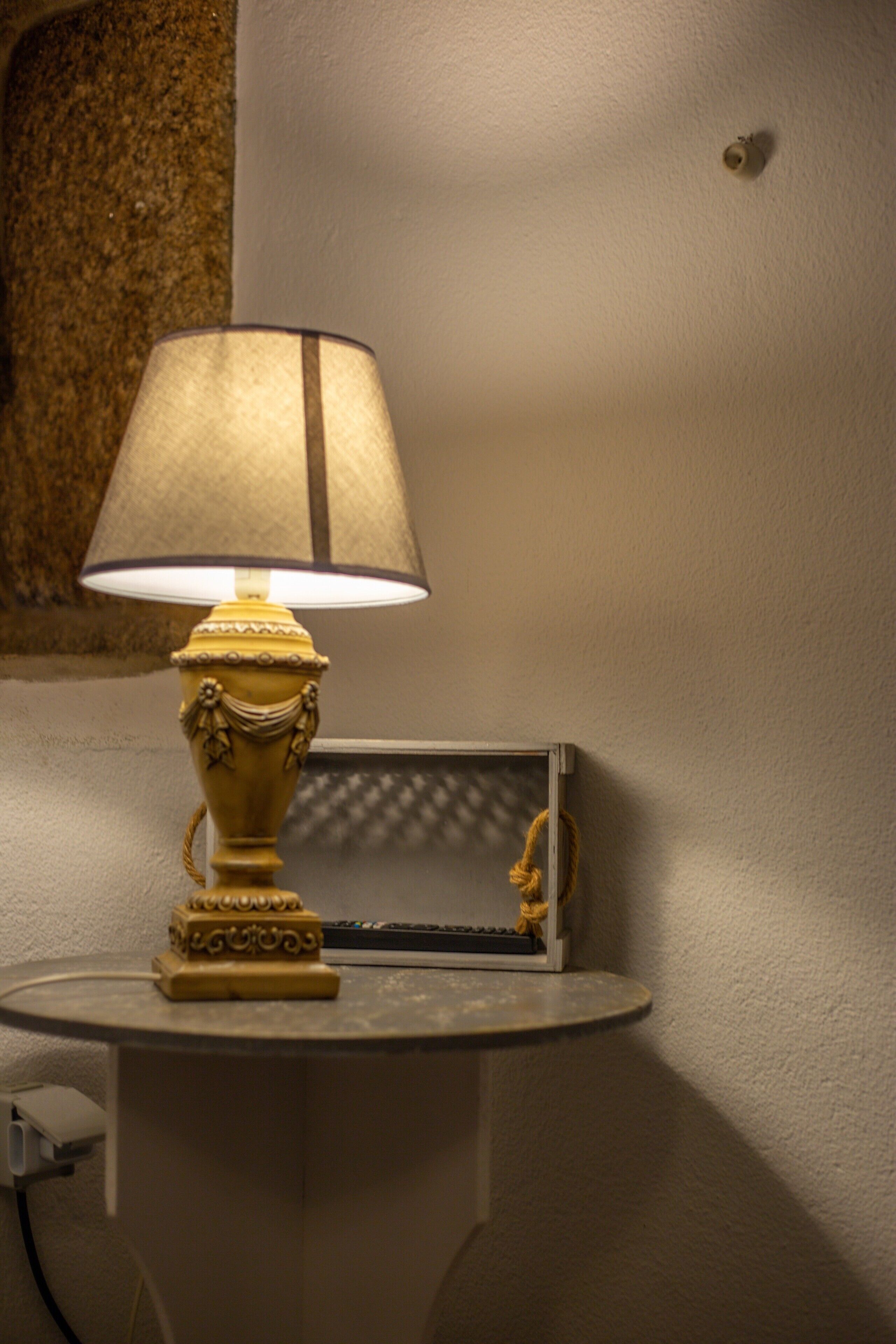 Una lámpara de mesa con pantalla, sobre una mesa frente a una pared.