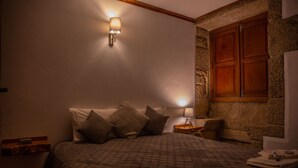 A bedroom with a bed, pillows, a nightstand with a lamp, and a wooden cabinet.