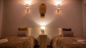 Ein Hotelzimmer mit zwei Betten, einem kleinen Tisch mit Lampe und Wandleuchten.