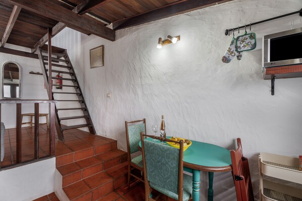 A dining area with a table, chairs, a staircase, and a wall-mounted TV.