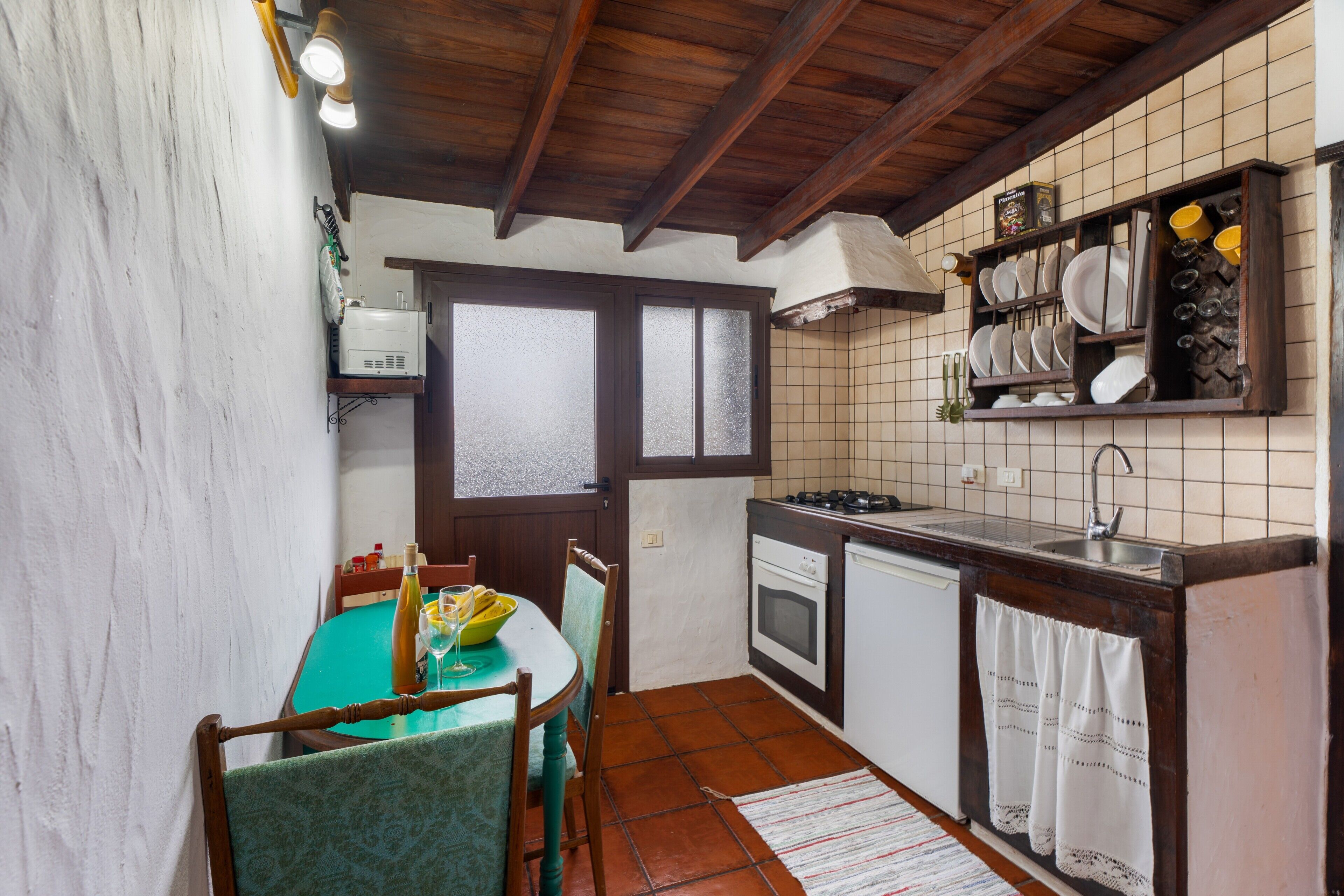 Cocina compacta con comedor, techo de madera y salpicadero de azulejos.