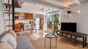 Una sala moderna con sofá, televisión y comedor con mobiliario de madera.