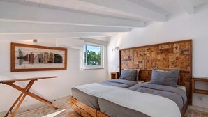 Un dormitorio con cama y cabecera de madera, una ventana y suelo de madera.
