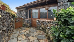 A stone house with a wooden door, a stone wall, and a stone-paved courtyard. - Apartment 'Tesbabo Rural - Mimo' with Sea View, Shared Garden and Wi-Fi (Mocanal)