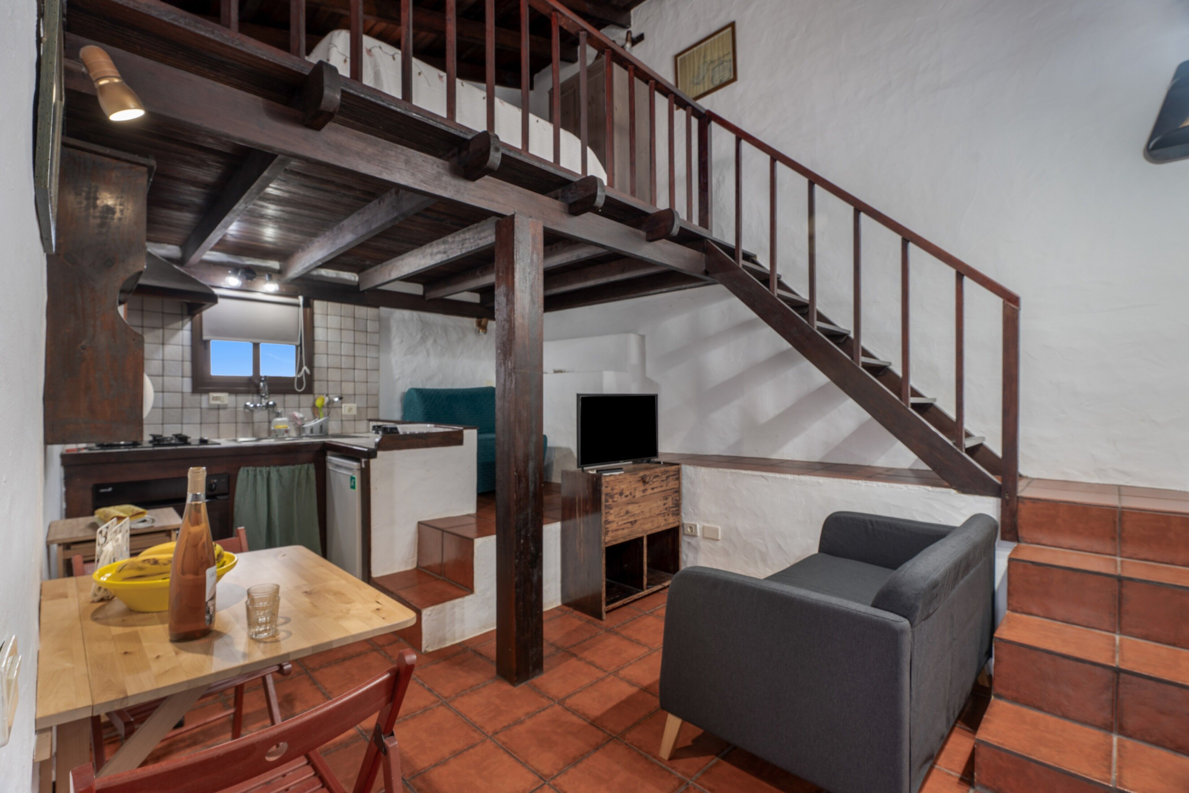 Un amplio salón con una escalera, una mesa de comedor y un sofá.