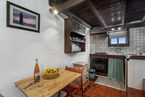 Une cuisine avec une table en bois, une bouteille et un saladier rempli de fruits.