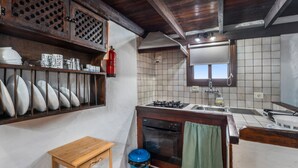 A kitchen with a stove, oven, and sink. There is a wooden table and a blue trash bin. - Apartment 'Tesbabo Rural - Mimo' with Sea View, Shared Garden and Wi-Fi (Mocanal)