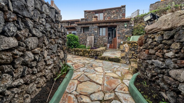 A stone pathway leading to a stone house with a wooden door and windows. - Apartment 'Tesbabo Rural - Mimo' with Sea View, Shared Garden and Wi-Fi (Mocanal)