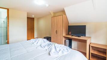 Un dormitorio con una cama, un televisor sobre un mueble de madera y un armario.