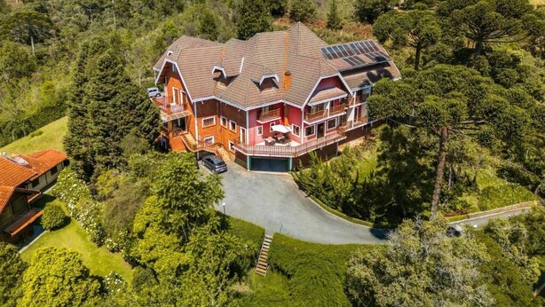 A large, two-story house with a spacious front yard, a driveway, and solar panels on the roof. - Serra do Jordão by Concavus (Campos do Jordão)