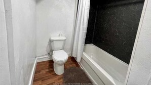Ein kleines Badezimmer mit Toilette, einer Badewanne und einer Duschvorhang.
