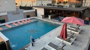 A rooftop pool with lounge chairs and umbrellas, surrounded by buildings and a clear sky. - “Freiheit Loft” Lush Couple’s Getaway by Gruene (New Braunfels)