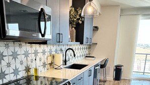 A modern kitchen with a large island, stainless steel appliances, and a star-patterned backsplash. - “Freiheit Loft” Lush Couple’s Getaway by Gruene (New Braunfels)