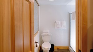 Een smalle gang die leidt naar een badkamer met een toilet, een handdoekhouder en een raam.