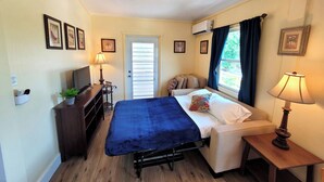 A compact bedroom with a bed, bedside table, lamp, and a TV. - Sunny 1 bedroom in Esperanza close to everything (Vieques)