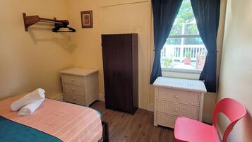 Quarto com cama, guarda-roupa, penteadeira, cadeira e janela com cortinas.